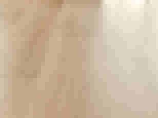 Lichthouten laminaatvloer met gladde planken in een warme beige tint, in perspectief gefotografeerd.