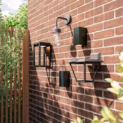 Lampe murale extérieure sur un mur de briques avec appliques noires et chaise pliante métallique.