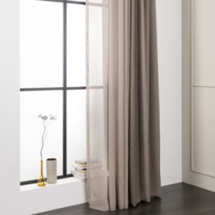 Une pièce moderne avec une grande fenêtre, des rideaux beiges, de petits objets décoratifs sur le rebord de la fenêtre et une décoration intérieure minimaliste.