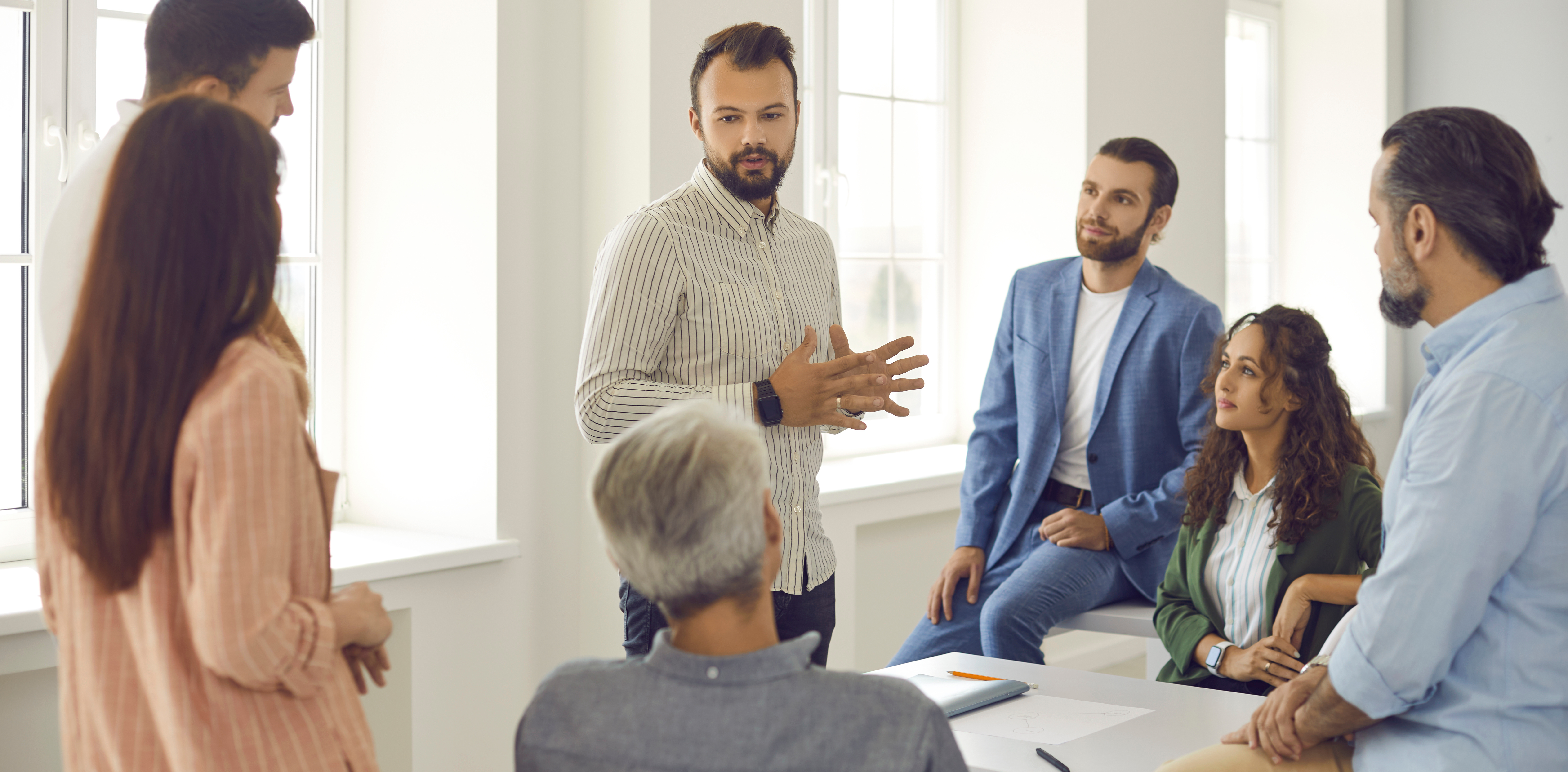 Group of working professional standing around a table talking. 