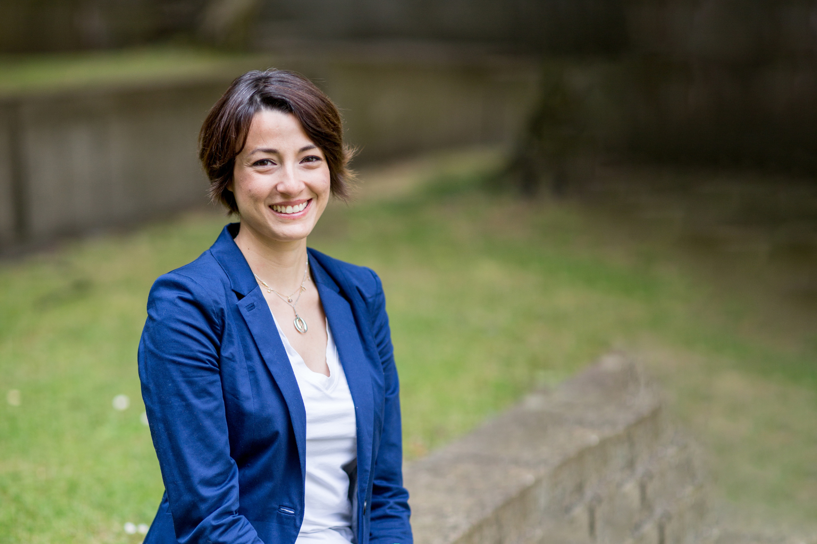 Woman in professional clothes stands, smiling, looking to camera.