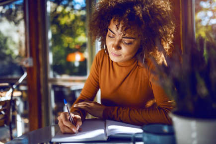 Young woman writing in journal at a cafe