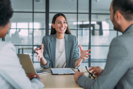Business woman smiling and presenting to her colleagues round a table