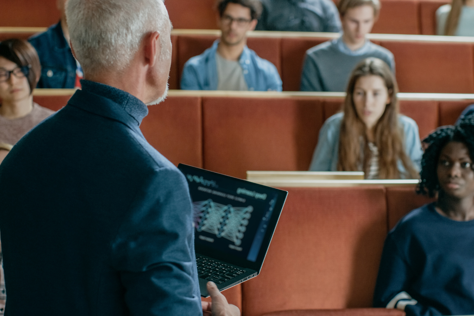 Professional man stands in a lecture theatre delivering a lecture