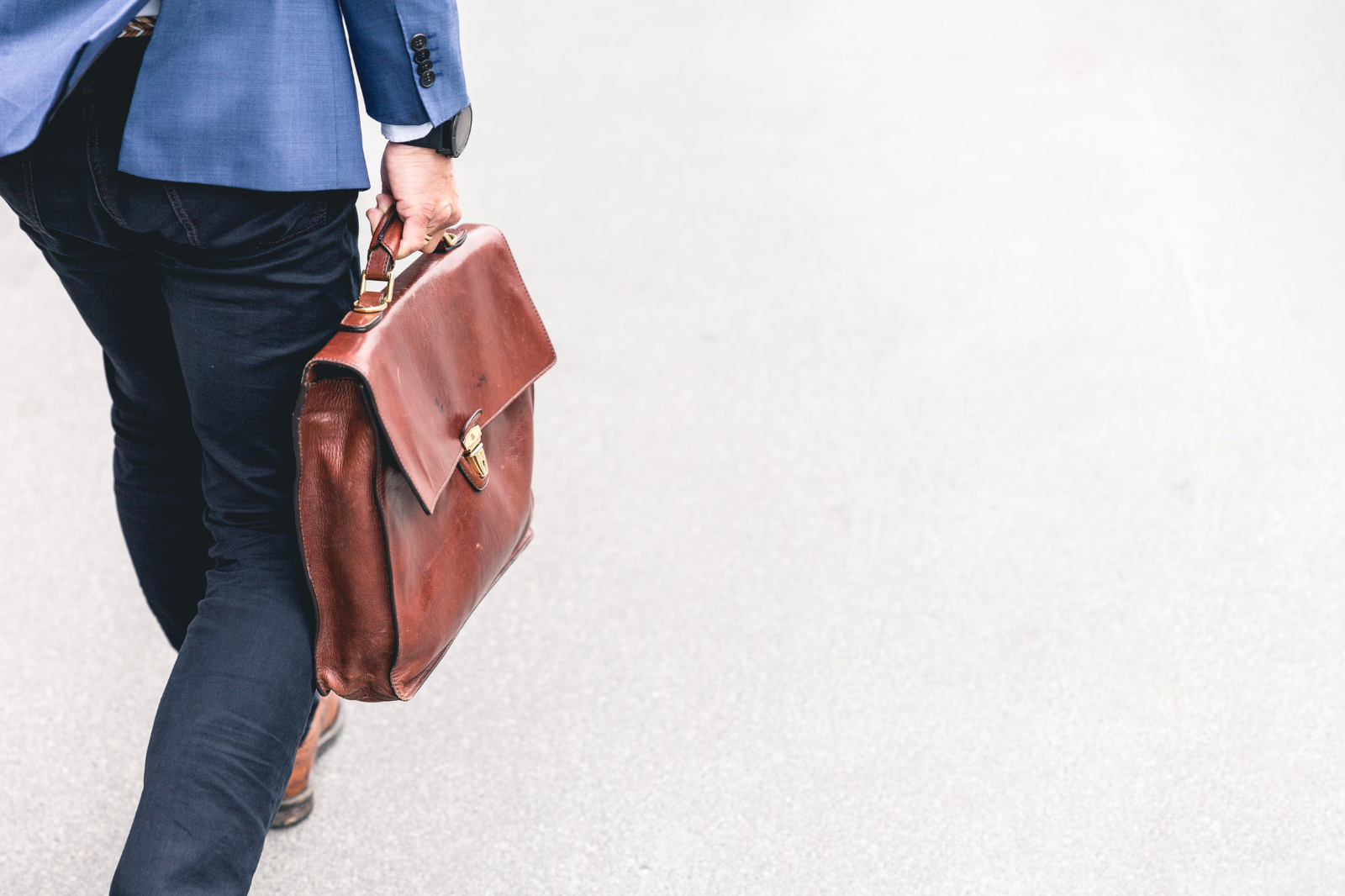 Close up of trousered individual walking holding a briefcase