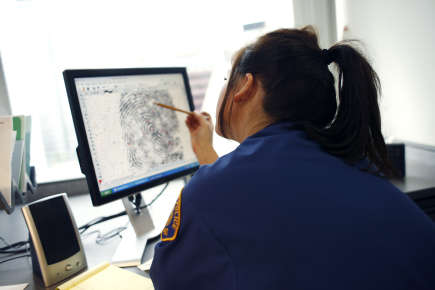 A young officer viewing a fingerprint on a computer.
