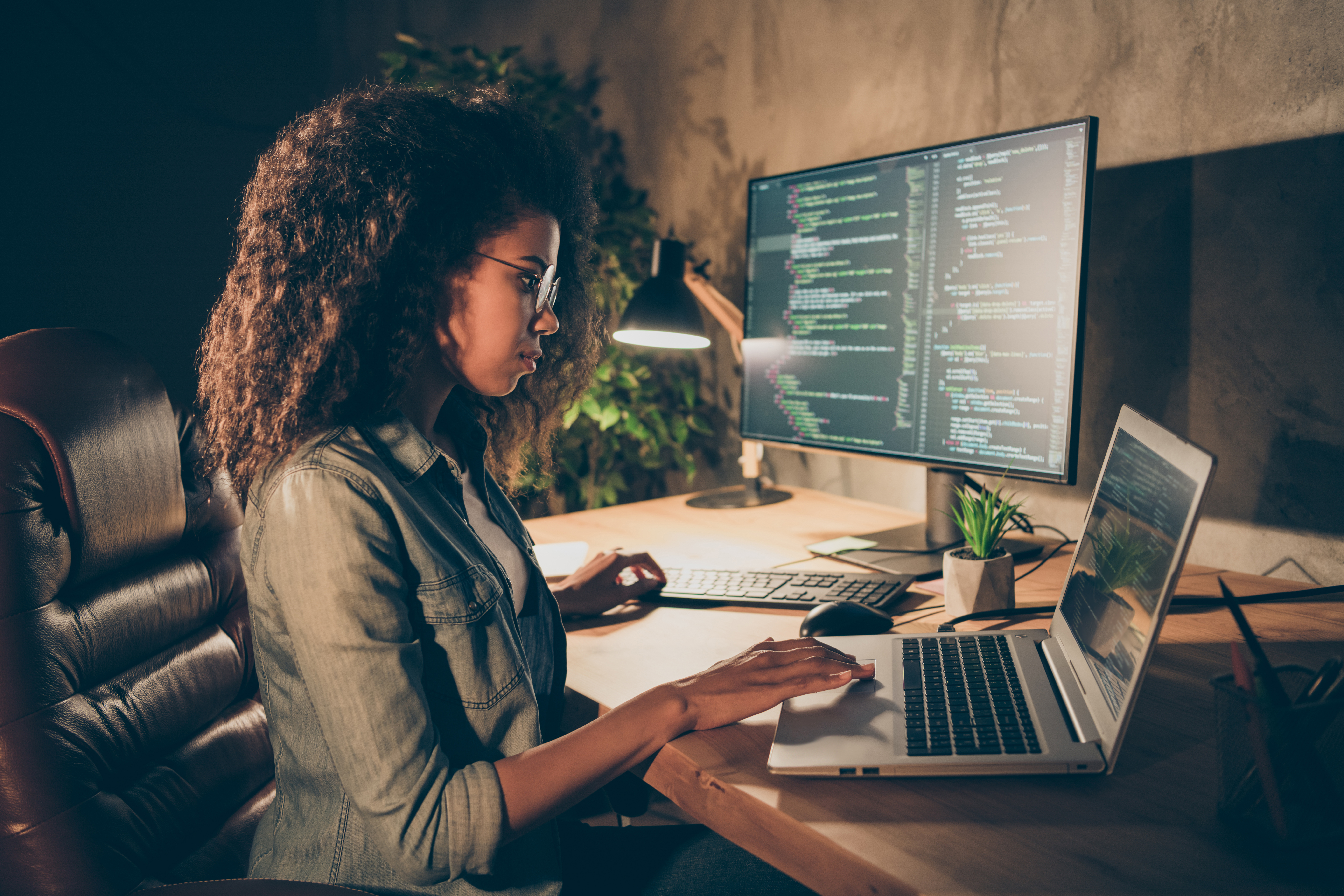 Woman working over two monitors wearing business attire