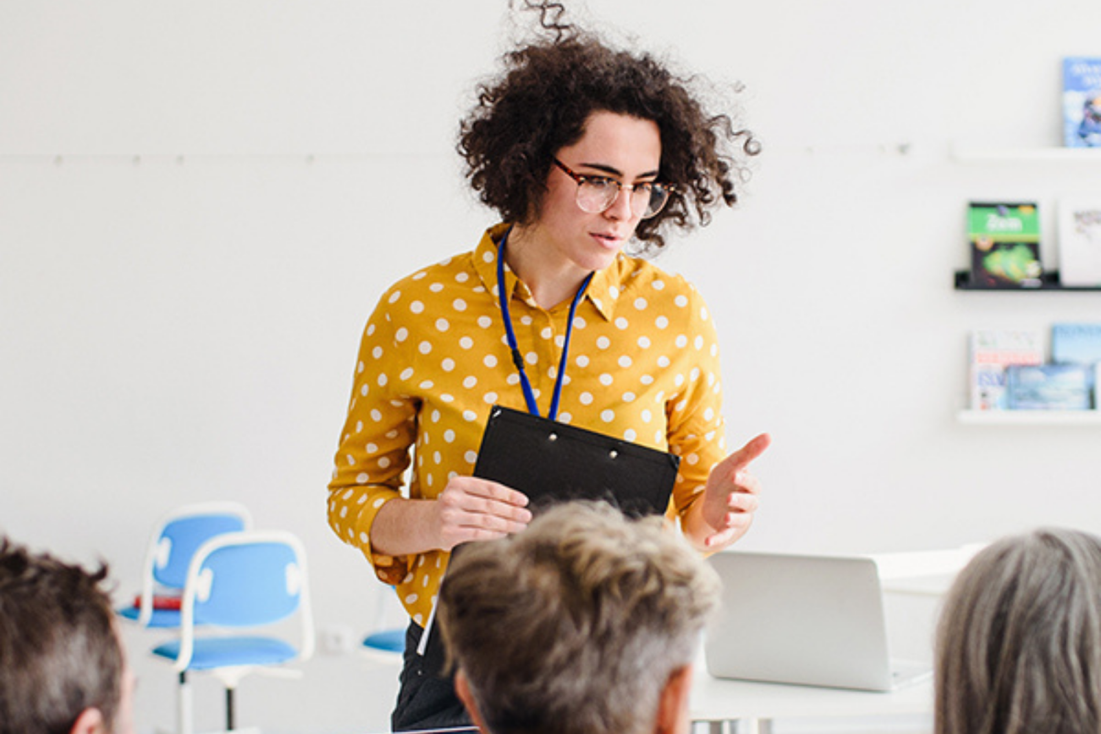 Image of professional leading a workshop, holding a clipboard in front of an audience.