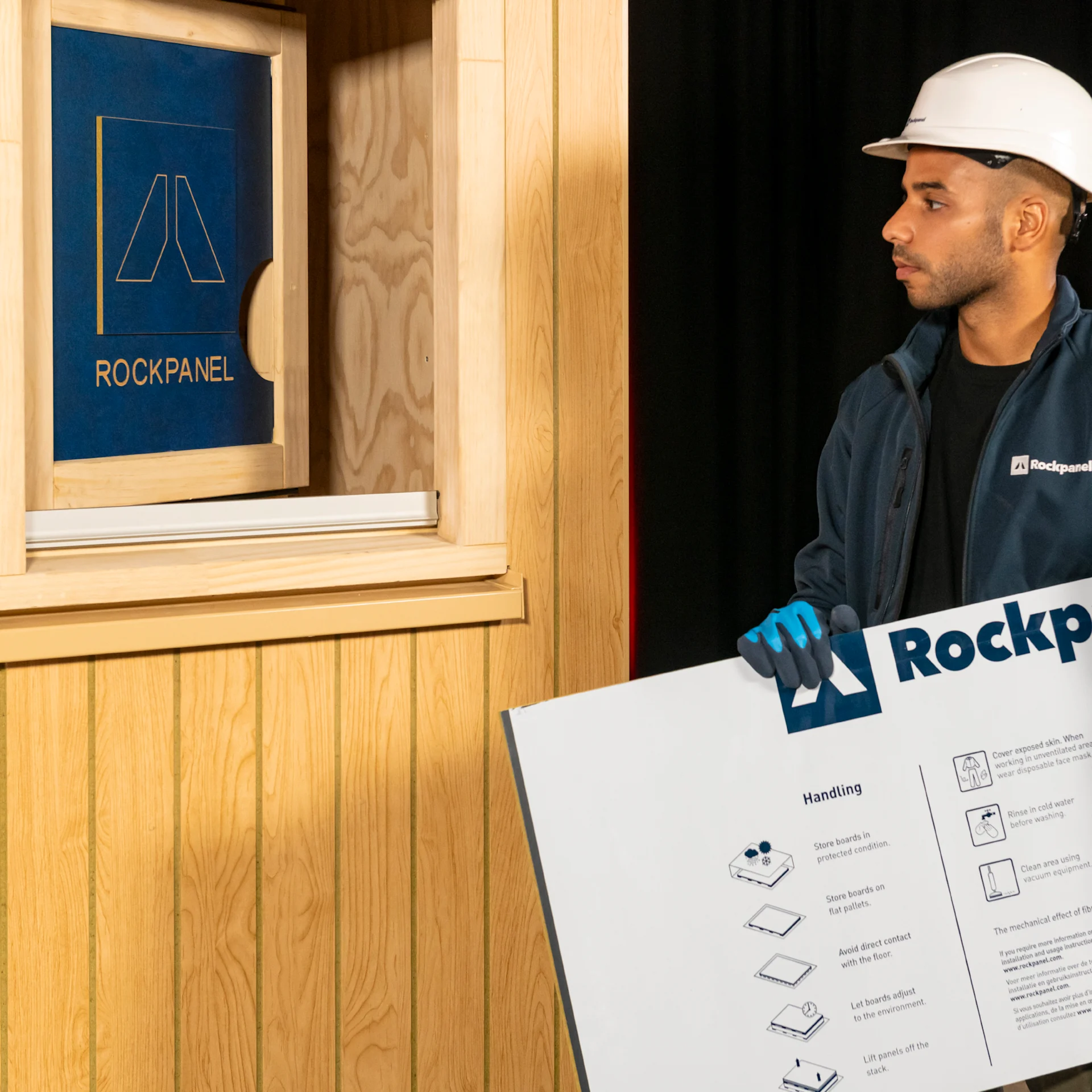 Mand bærer Rockpanel plade for at montere den på facade ved vindue.