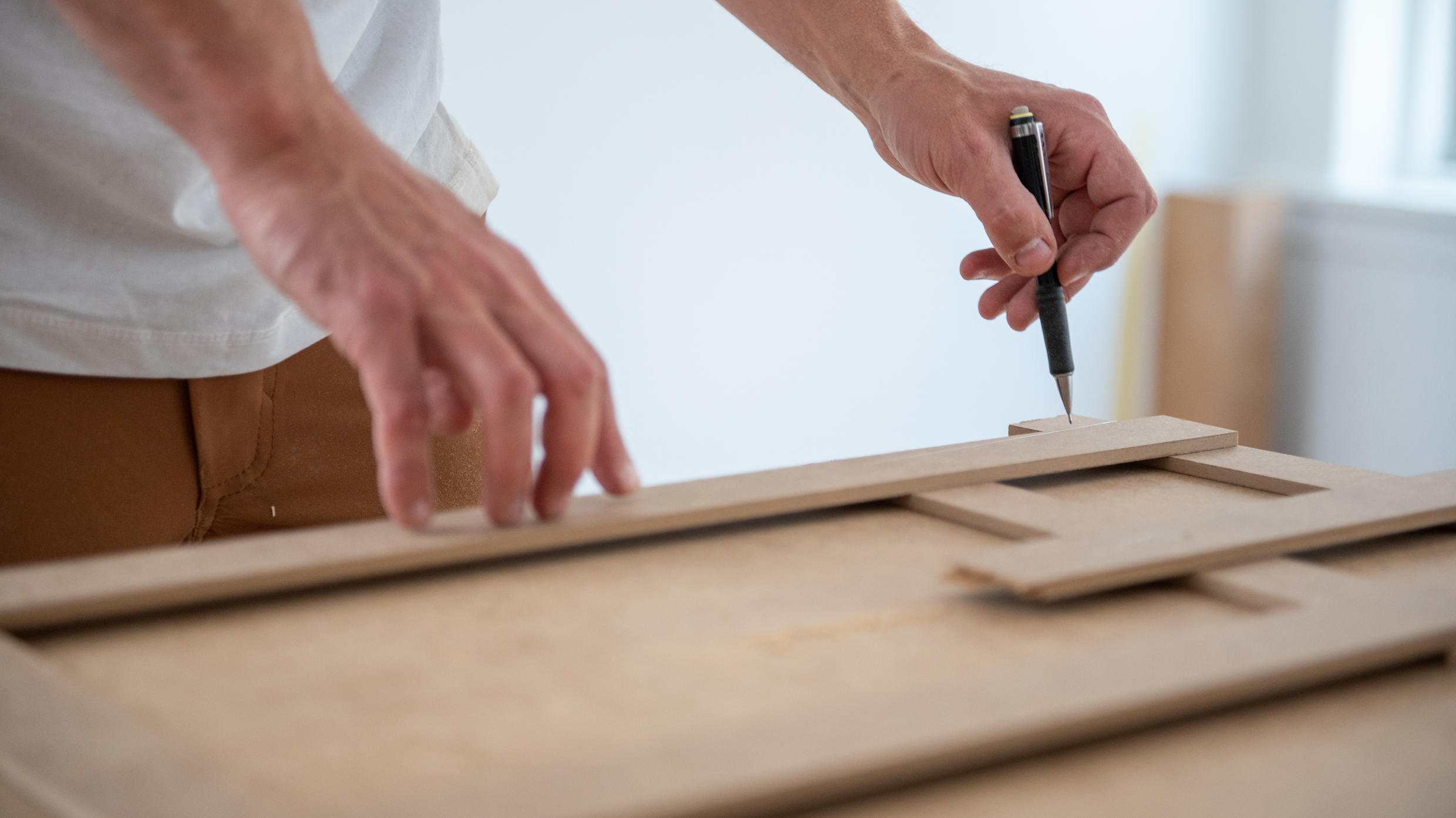 Mandehånd tegner på træplade.