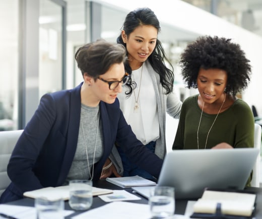 Three coworkers discussing information shown on laptop screen