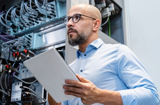 IT professional holding tablet inspecting technical equipment