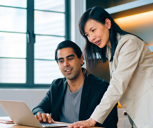 Two coworkers looking at laptop