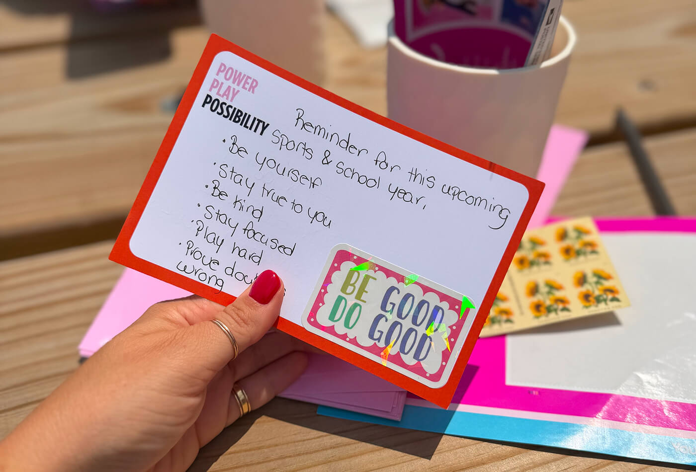 A close-up of a hand-written card that reads “Power Play Possibility" with affirmations and a sticker that reads “Be Good Do Good.” 