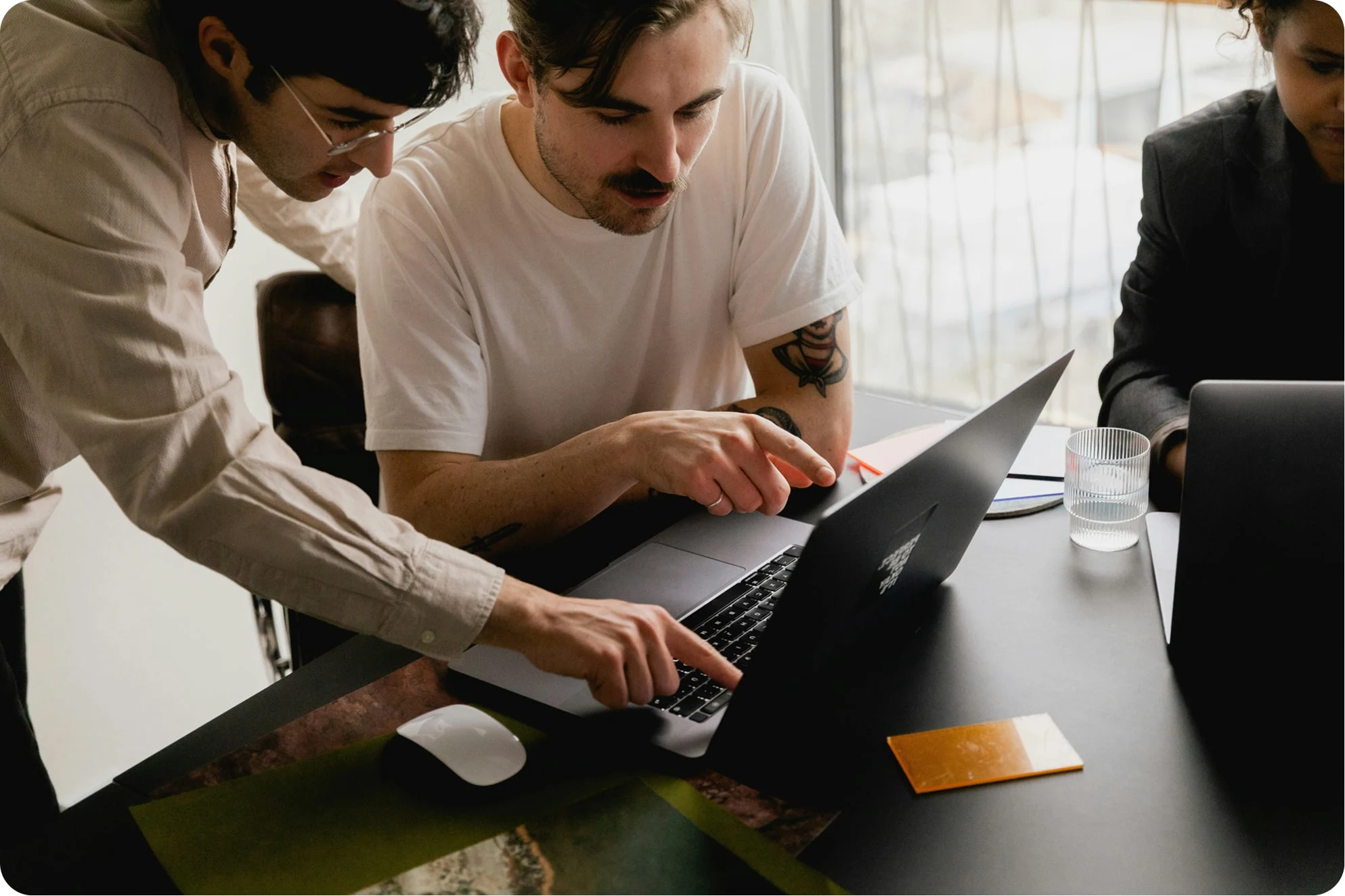 Two people leaning over a laptop at a table, pointing at the screen as they work together.