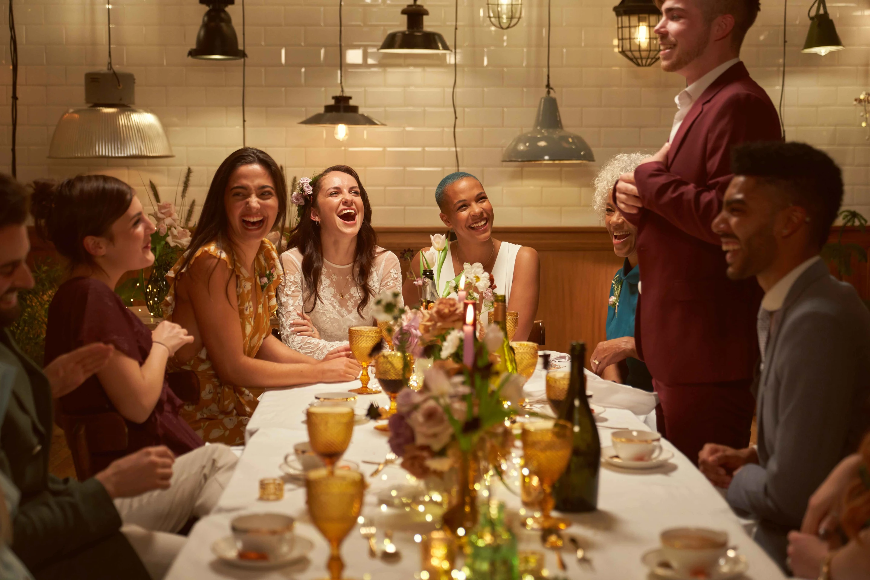 A couple celebrates at their wedding dinner party surrounded by guests