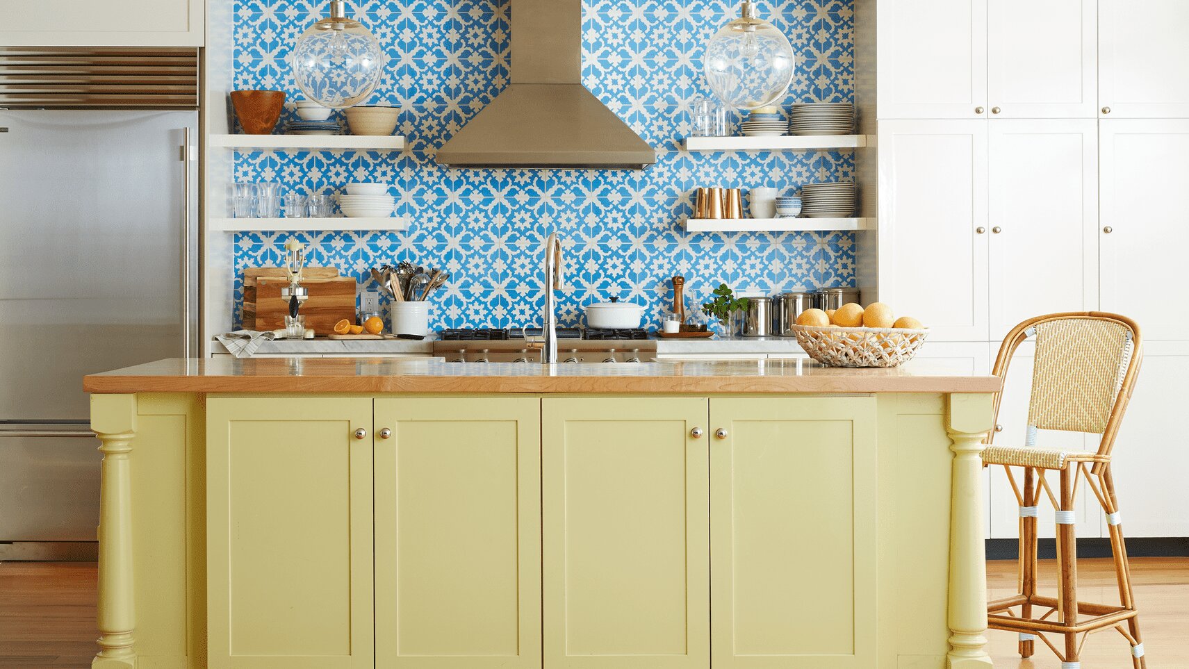 Sage green island, patterned blue tile, and vintage-modern touches bring playful, personal style to the kitchen.