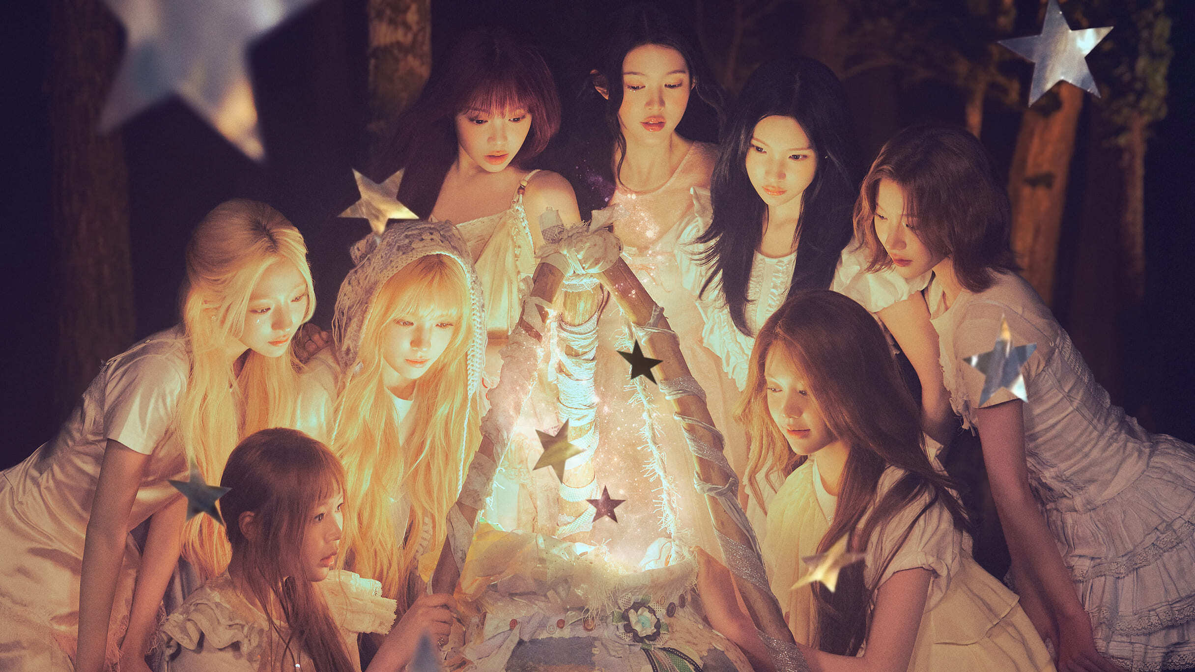 KPOPグループ Hearts2Hearts のメンバー8人が森の中で星の飾りがついた小さなテントを覗き込んでいる