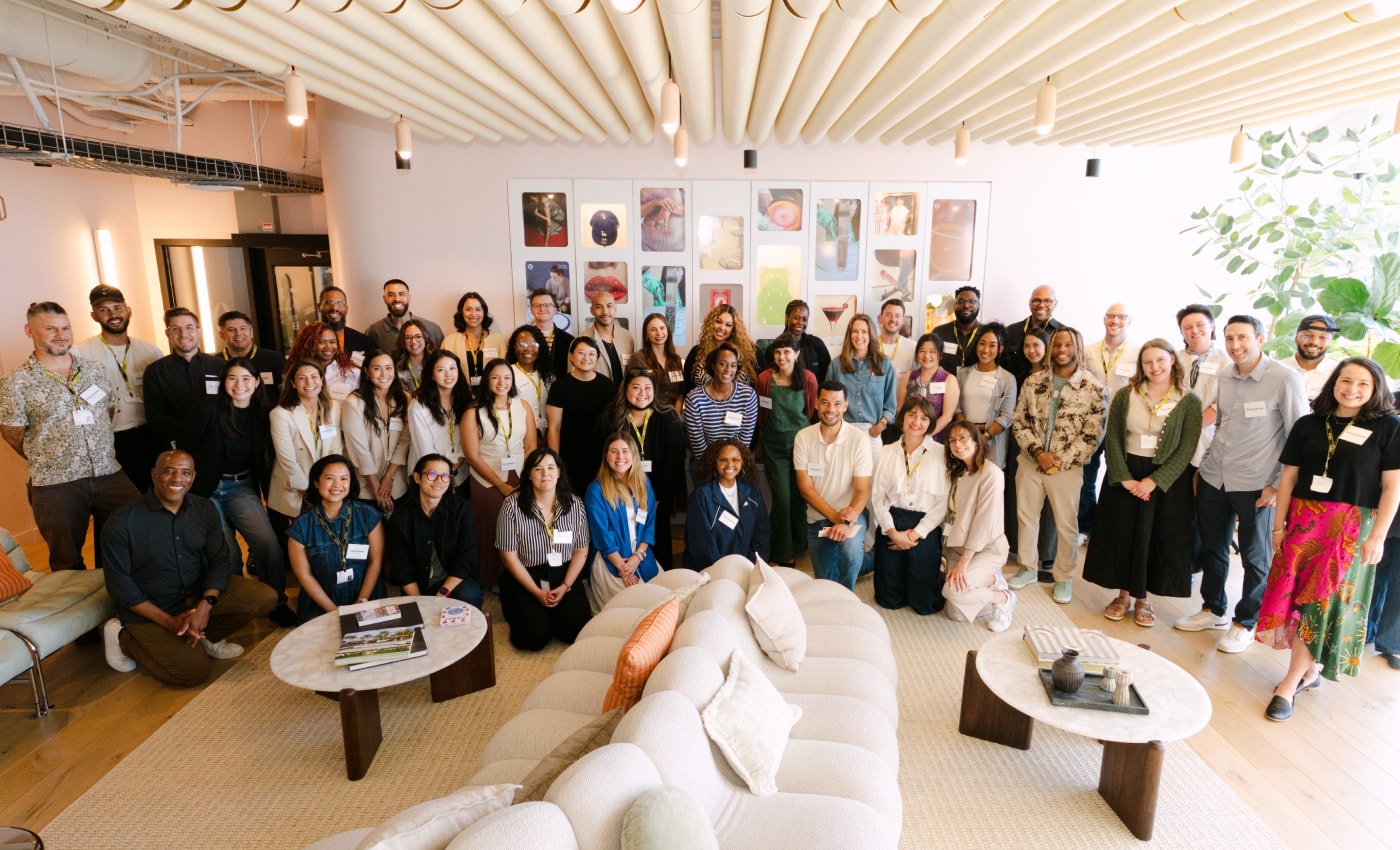 A group photo of people at the Impact Lab Summit posing and smiling together in a modern office space. 