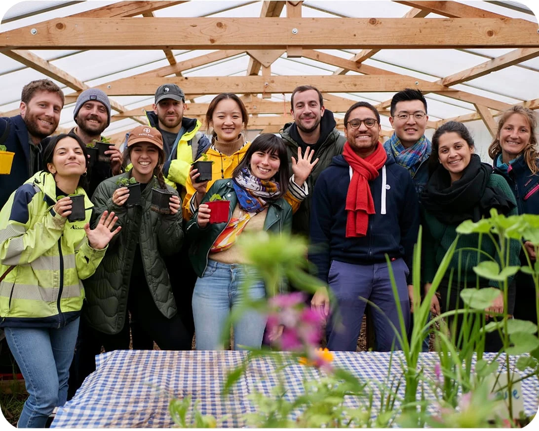 A smiling group of people pose for a photo in a greenhouse.