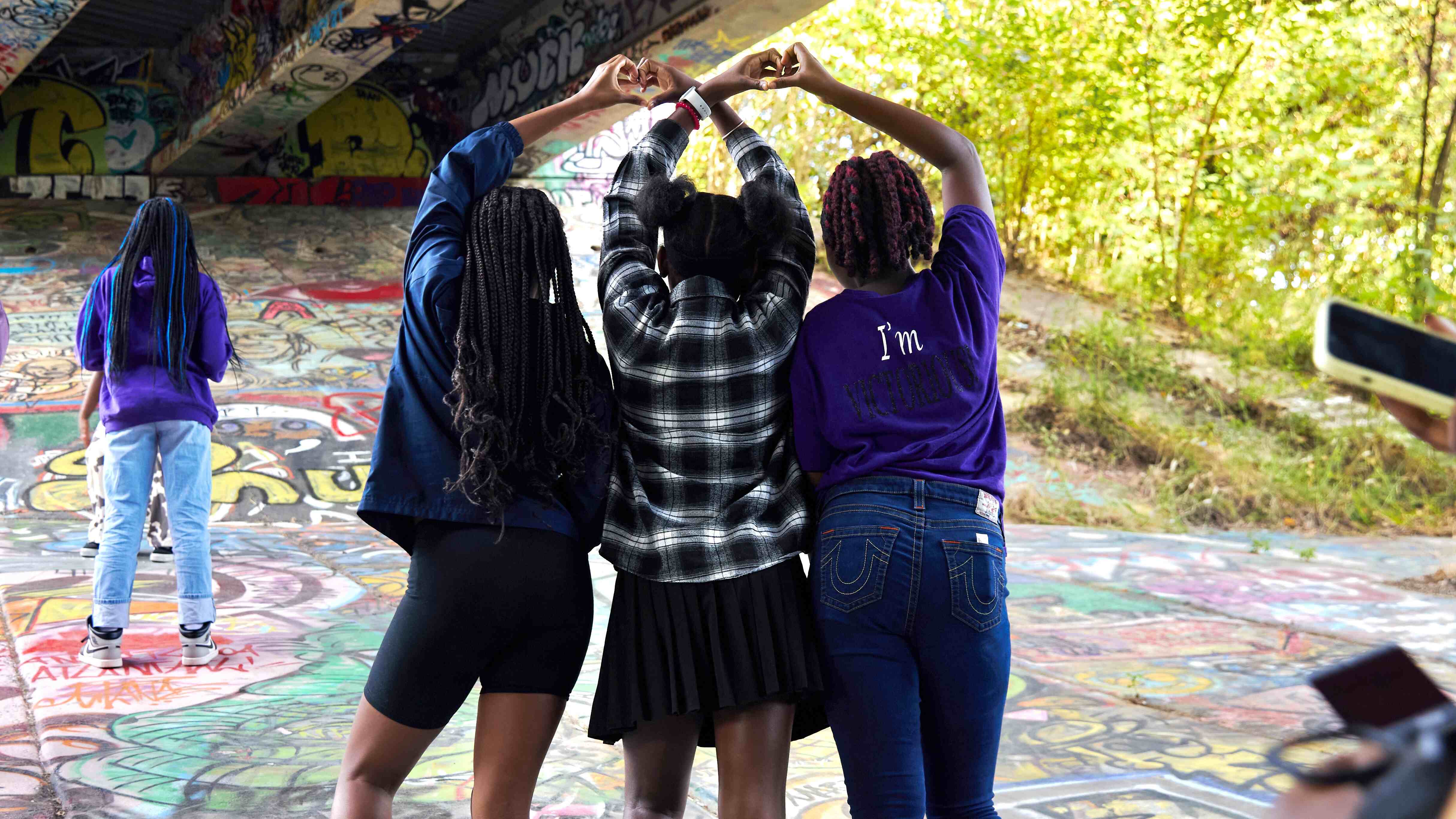 Teens with their back to camera using hands to make a heart shape