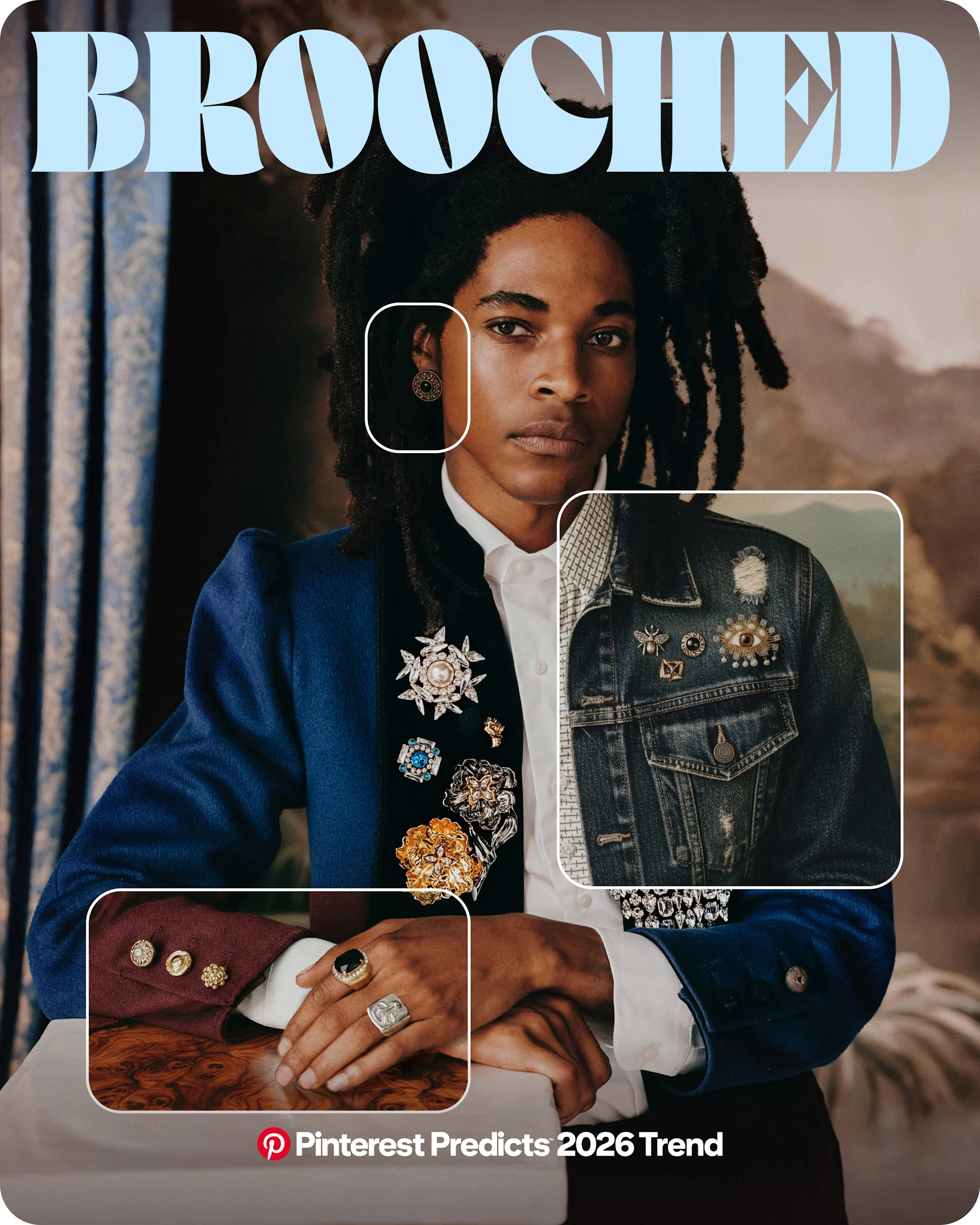 Someone leans against a white table with their hands crossed, wearing a blue blazer adorned with various brooches on the lapels.