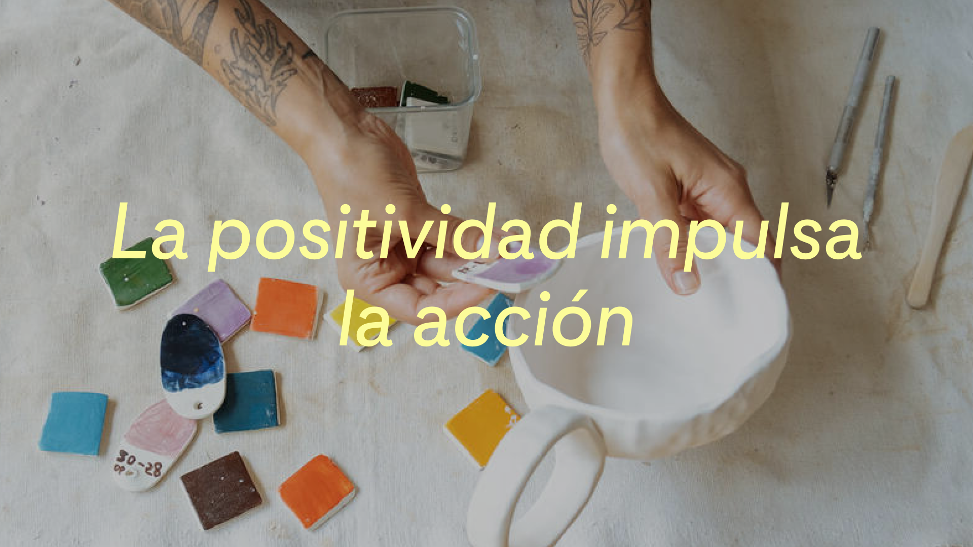Un ceramista prueba diferentes muestras de color en una taza hecha a mano. Las palabras "La positividad impulsa la acción" aparecen sobre la imagen 