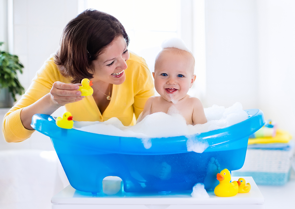 Mamá bañando a su guagua en bañera de bebé.