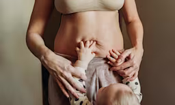 Baby reaching up, grabbing mom’s belly