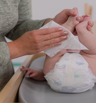 Imagen de una mamá limpiando la pierna del bebé durante un cambio de pañal