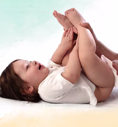 Un bebé está tumbado de espaldas sobre una superficie blanca, levantando los pies mientras un padre utiliza una toallita para limpiar el trasero del bebé. Un bebé está tumbado de espaldas sobre una superficie blanca, levantando los pies mientras un padre utiliza una toallita para limpiar el trasero del bebé.