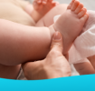  Adult lifting a baby’s legs while cleaning with a wipe.