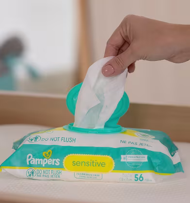 Mano sacando una toallita de un paquete de Pampers Sensitive Mano sacando una toallita de un paquete de Pampers Sensitive