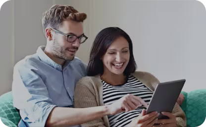 Mom and partner sitting on Sofa researching something online and smiling
