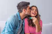 Couple celebrating positive pregnancy test with joy and affection.
