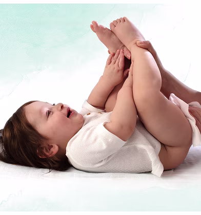 En baby ligger på rygg på en vit yta, håller upp sina fötter medan en förälder använder en våtservett för att rengöra babyns bak. En baby ligger på rygg på en vit yta, håller upp sina fötter medan en förälder använder en våtservett för att rengöra babyns bak.