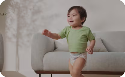 Toddler smiling in living room wearing Pampers