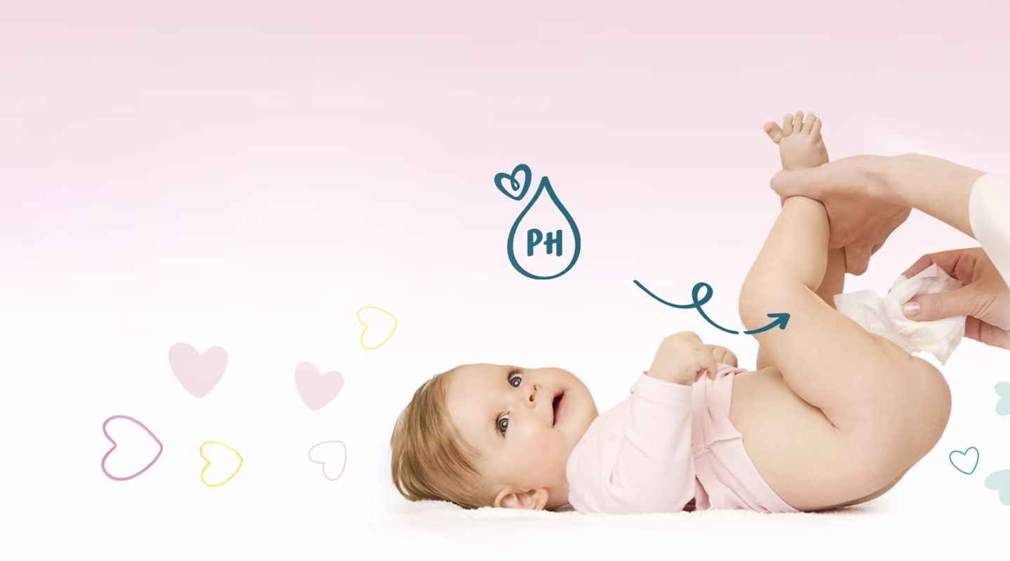 En baby ligger på ryggen mens en person tørker babyens rumpe med en våtserviett.