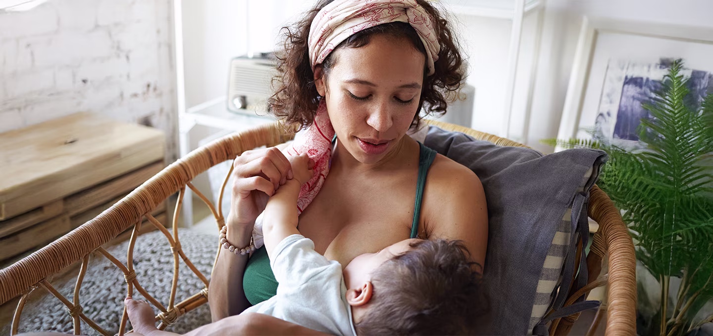 Mother lovingly breastfeeding her baby in a cozy setting.