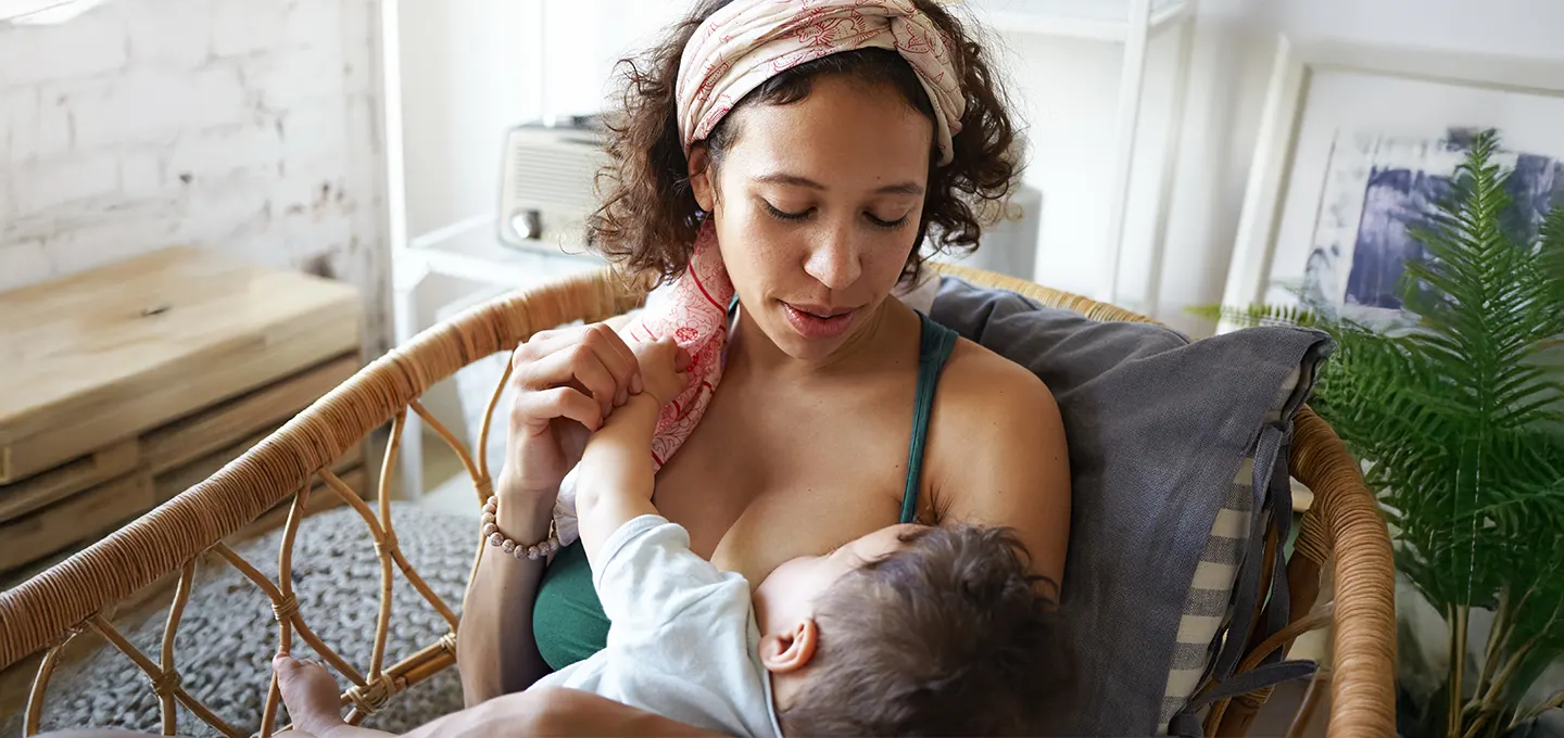 Mother lovingly breastfeeding her baby in a cozy setting.