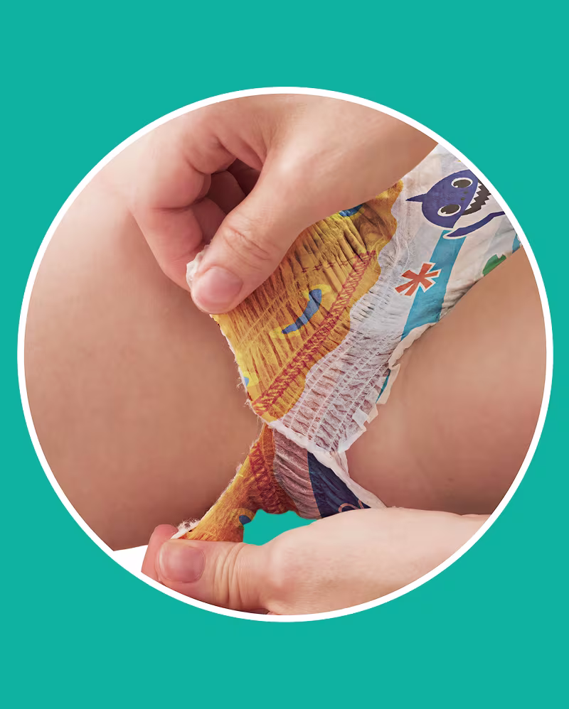 Deux mains déchirent les bandes latérales des Pampers® Splashers et illustrent la facilité du retrait.
