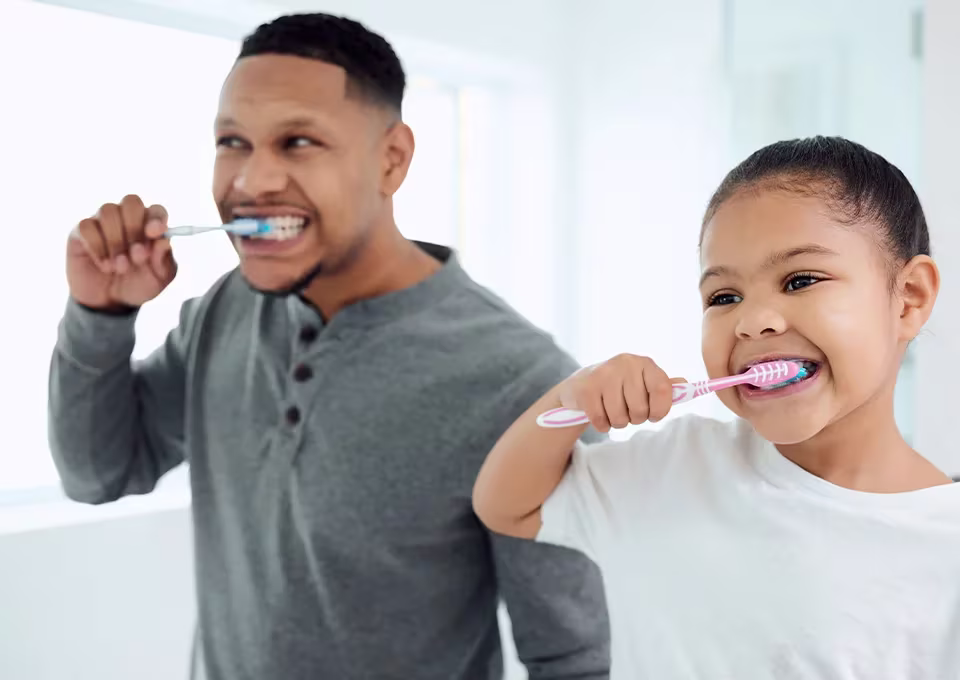 Criança escovando os dentes com o papai