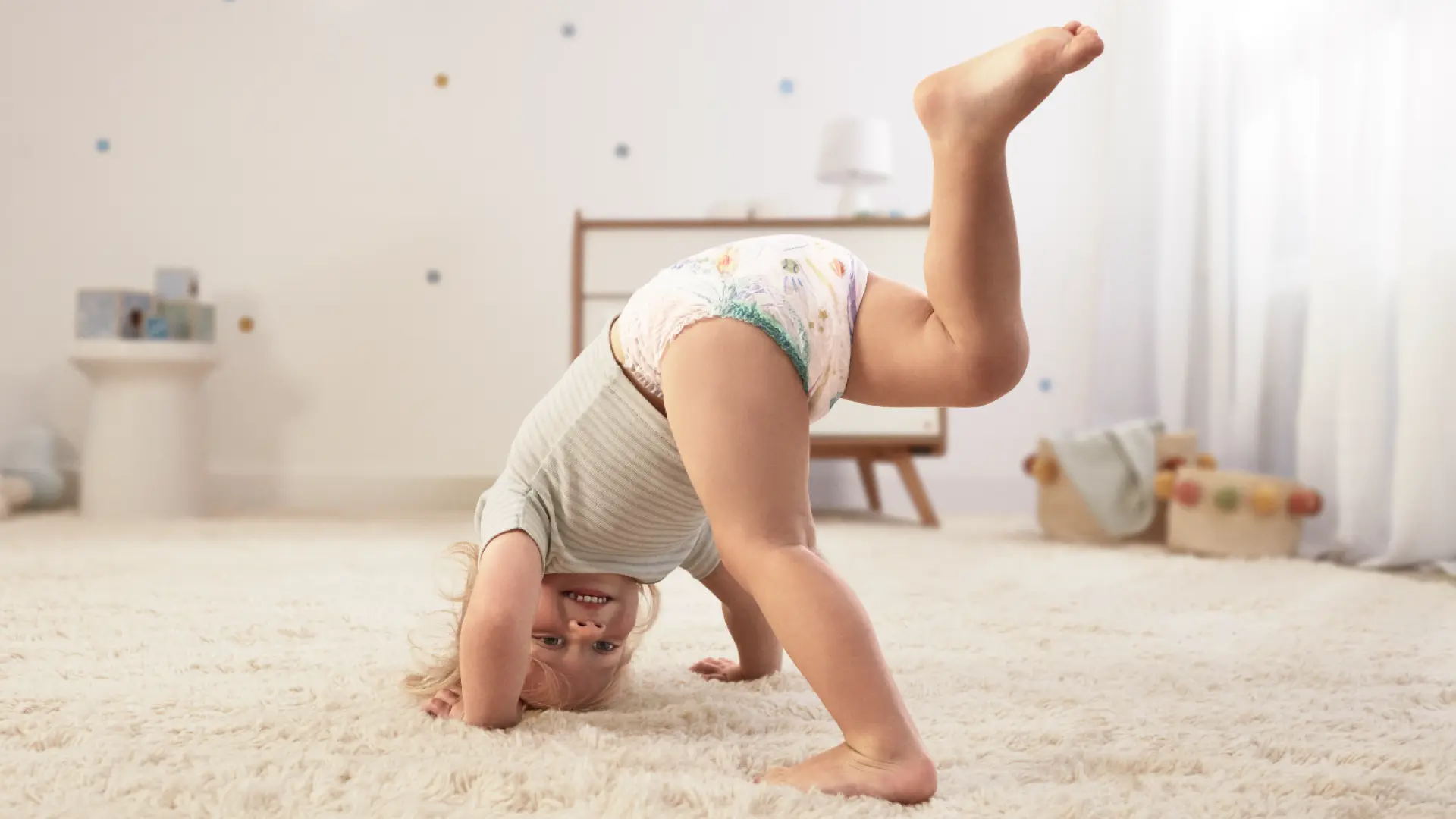 Batole, které se pohybuje po koberci a má na sobě Pampers Pants