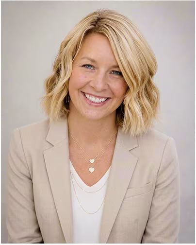 A female scientist with blonde hair and blue eyes and short wavy hair smiles.