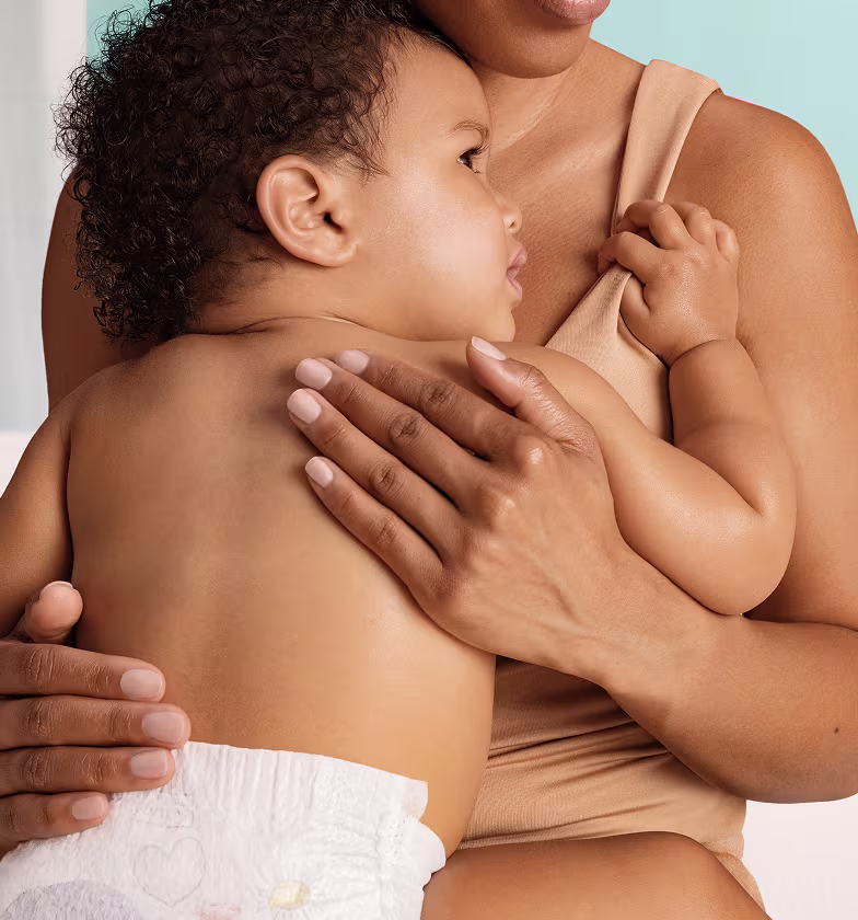Un gros plan montre une mère tenant tendrement son bébé contre sa poitrine.