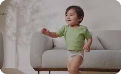Χαμογελαστό μωρό με πάνες Pampers, που στέκεται στο σαλόνι
