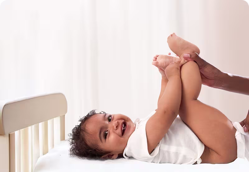 Et nærbilde av et babys ansikt mens en hånd forsiktig tørker kinnet deres med en Pampers Harmonie Aqua-wipe.