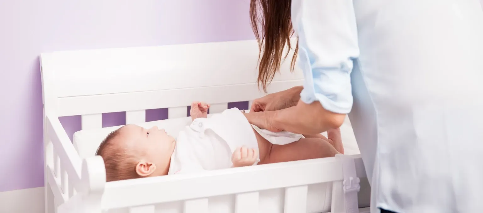 Mamá previniendo filtraciones de pañal a su bebé Mamá previniendo filtraciones de pañal a su bebé