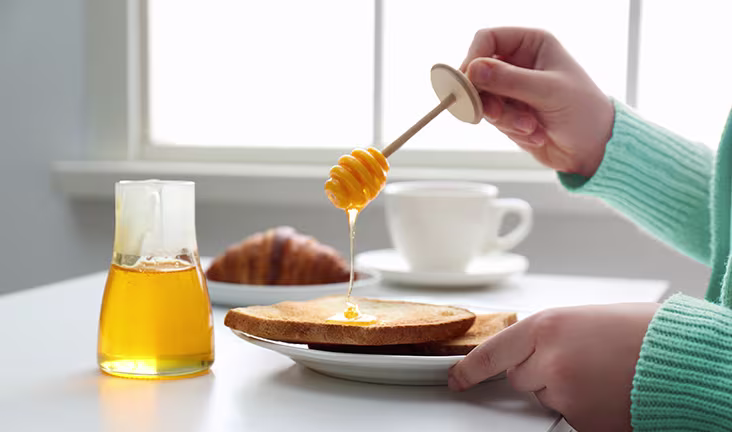 Schwangere Frau schmiert Honig aufs Brot