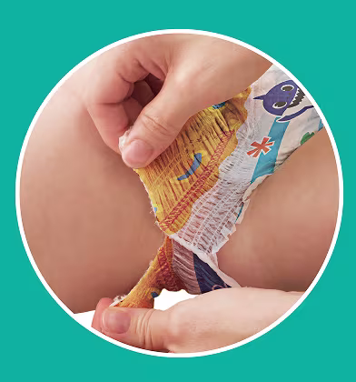 Prim-plan pe mâini care rup lateralul scutecului de baie cu motiv Baby Shark de pe partea inferioară a corpului copilului. Prim-plan pe mâini care rup lateralul scutecului de baie cu motiv Baby Shark de pe partea inferioară a corpului copilului.